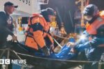 Rescuers leave a vessel while carrying a man, who was reportedly saved after his sailboat had drifted for 67 days in waters edging the north-western Pacific