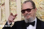 Gary Oldman in a dinner jacket on the red carpet at the Golden Globe Awards in January, pointing off camera