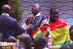 An MP wrapped in a Ghanaian flag stands up in parliament - 22 October 2024