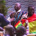 An MP wrapped in a Ghanaian flag stands up in parliament - 22 October 2024